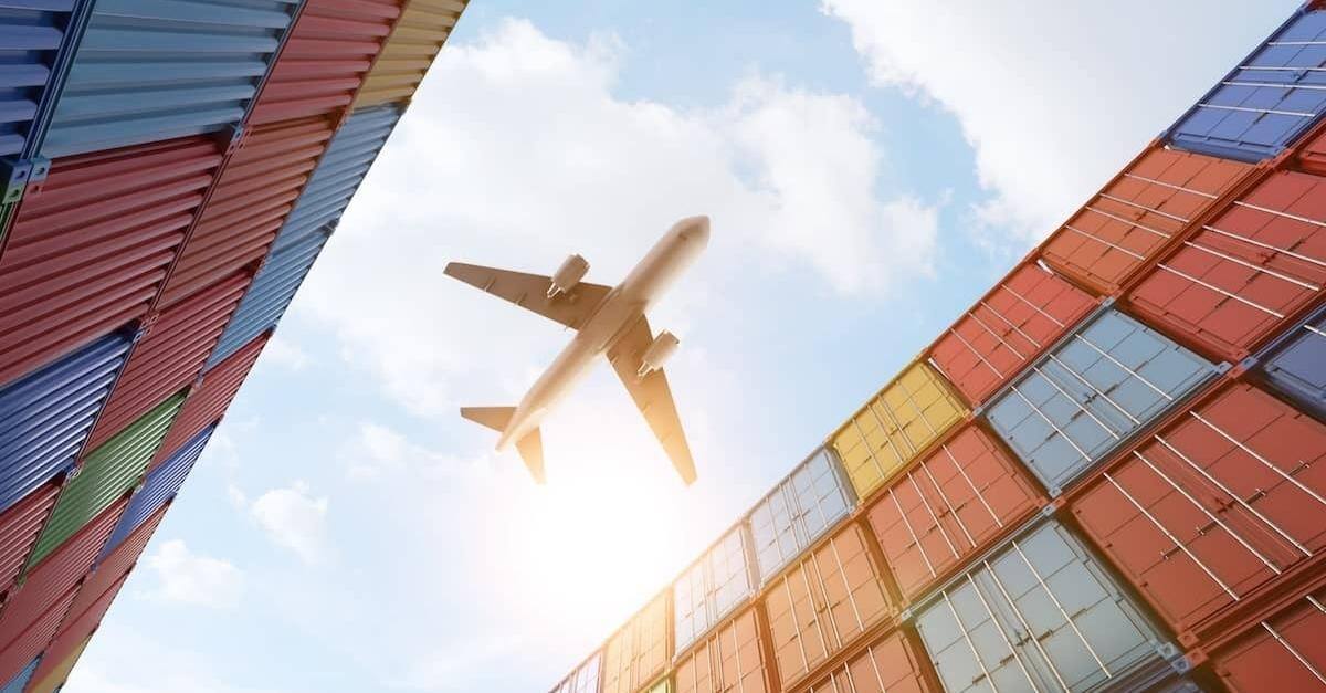 An airplane flying over cargo containers